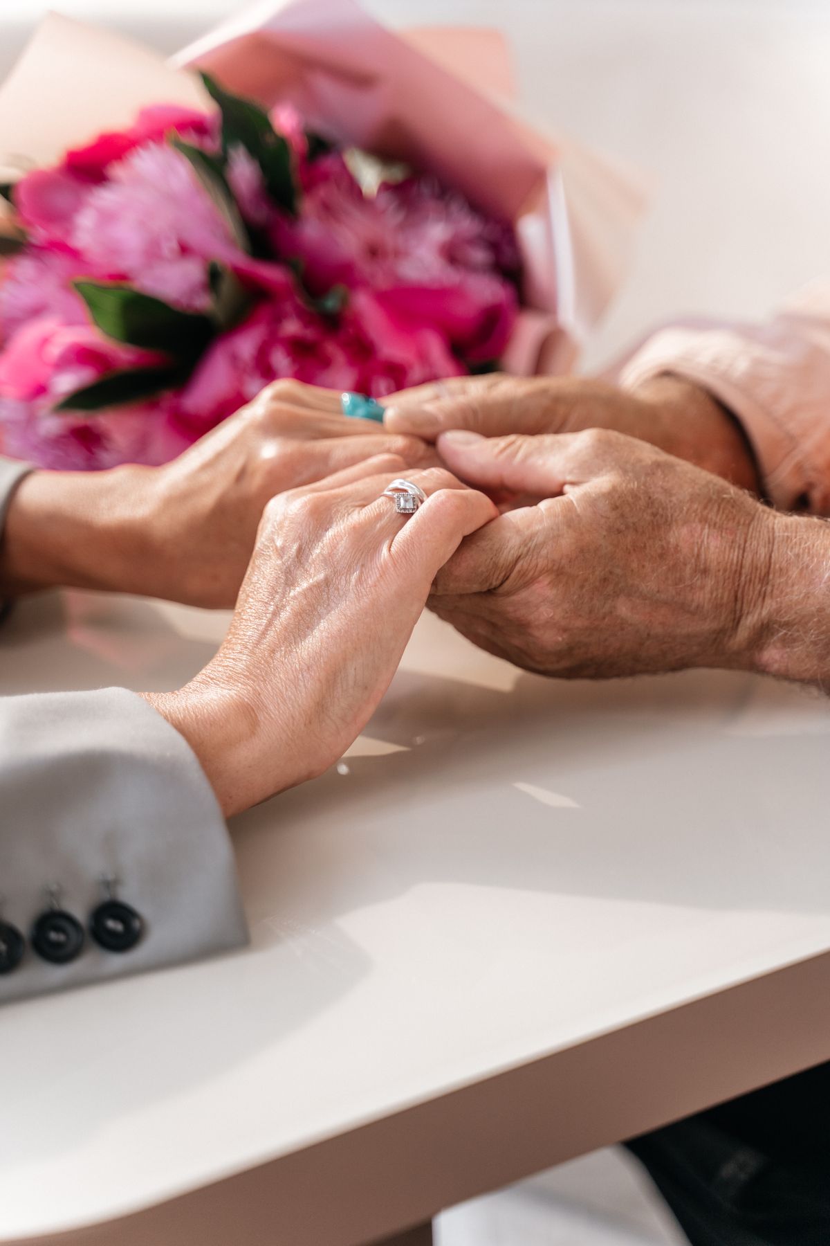 An older couple holding hands with flowers